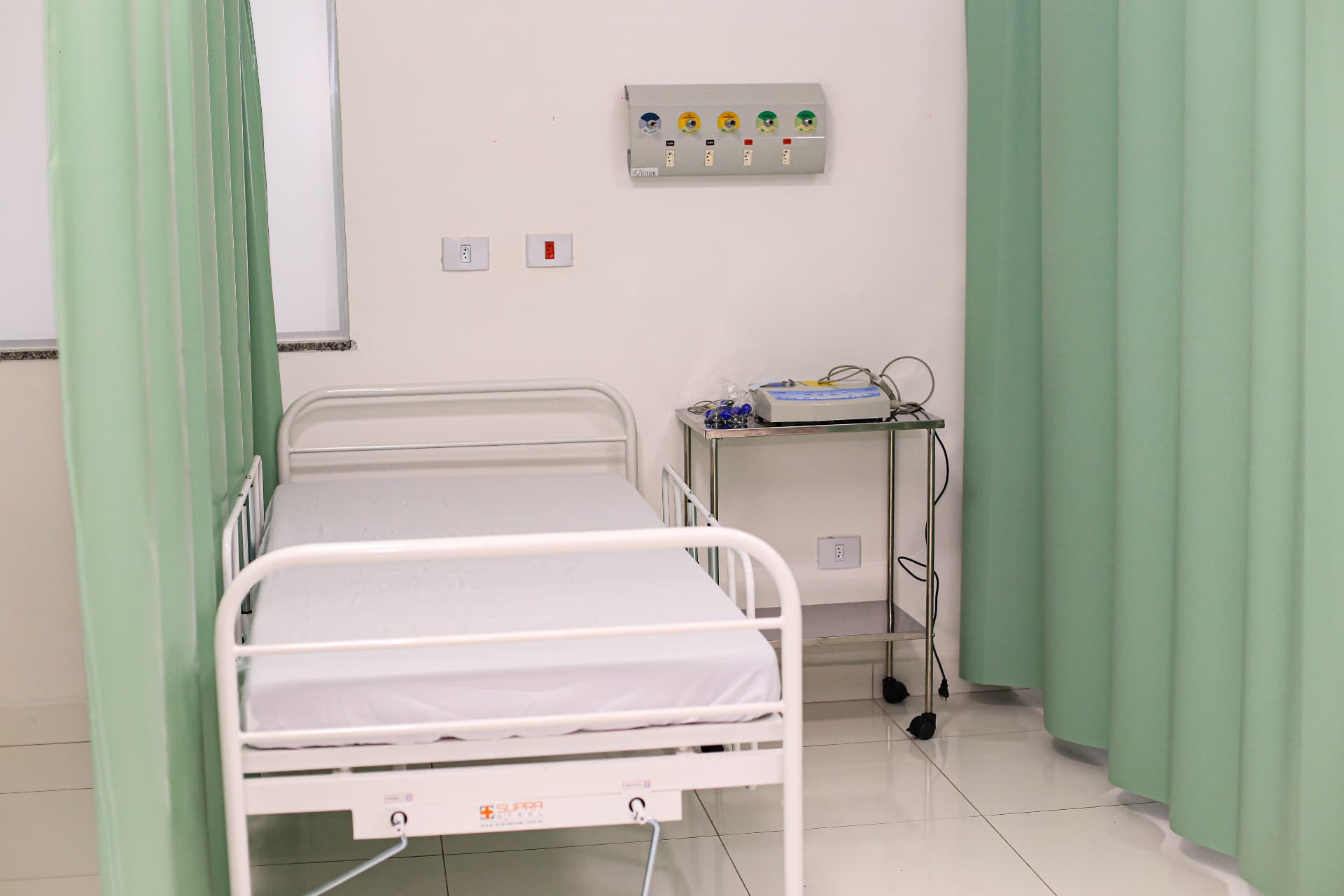 Leito hospitalar com divisórias e equipamentos de monitoramento