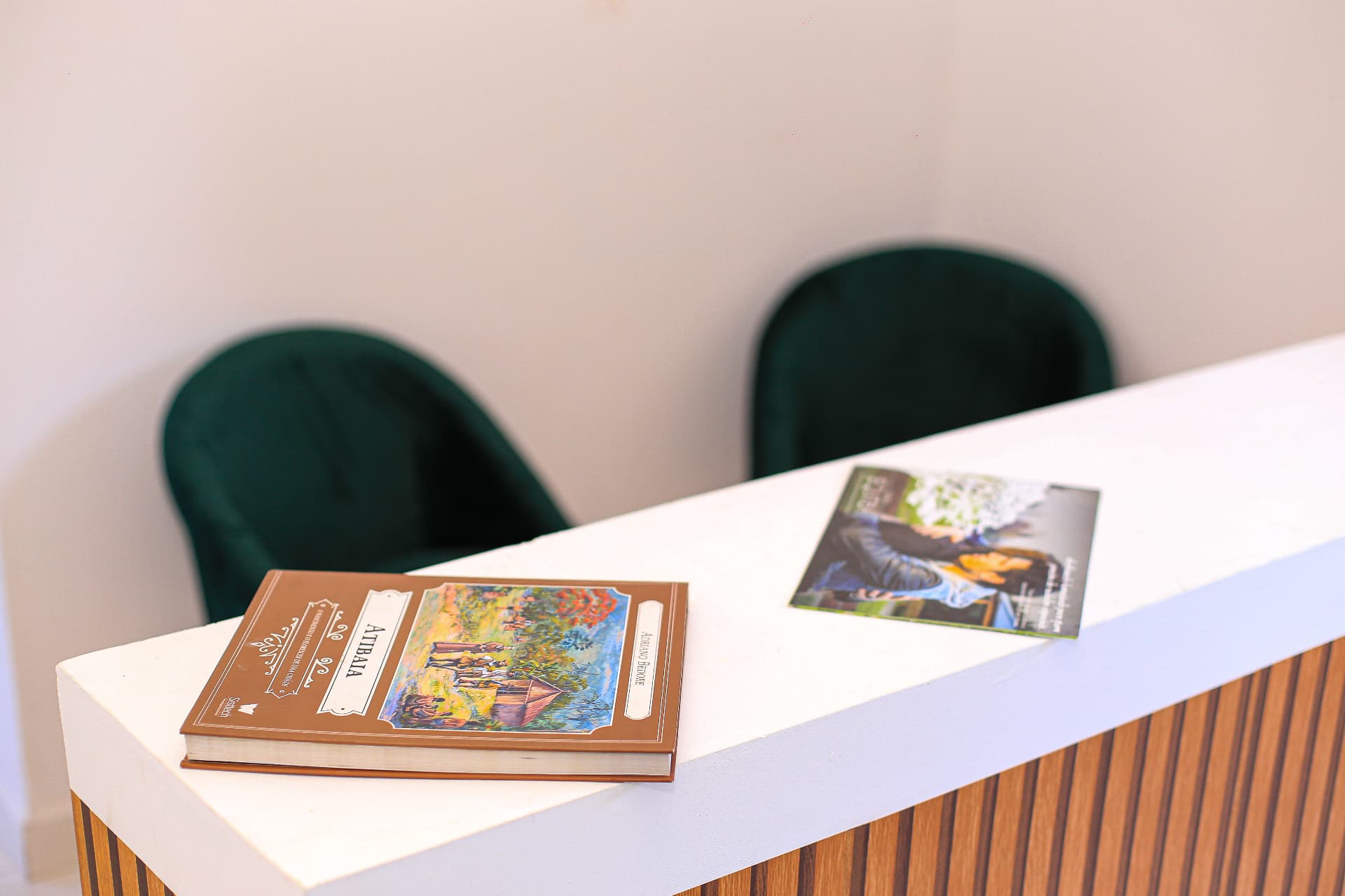 Sala de espera com poltronas verdes e balcão de atendimento